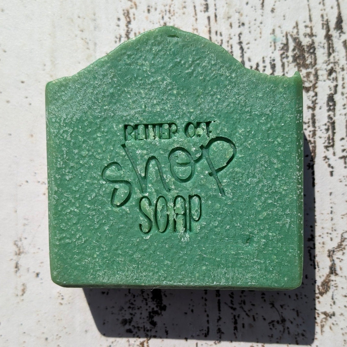 Green soap bar with 'Suds' branding on a wooden surface
