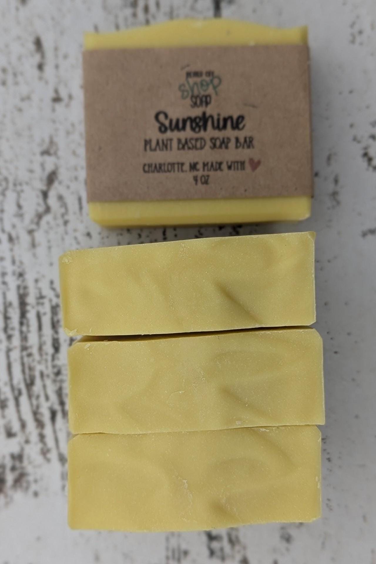 A vibrant yellow handmade cold process soap bar with beveled edges, wrapped in a recyclable paper band. The soap has a fresh, fruity citrus scent with notes of mandarin oranges, bergamot, tangerine, peaches, strawberries, raspberries, and white musk. Made with plant-based ingredients like castor oil, coconut oil, olive oil, and shea butter for a moisturizing lather. Ideal for eco-conscious skincare and daily self-care.