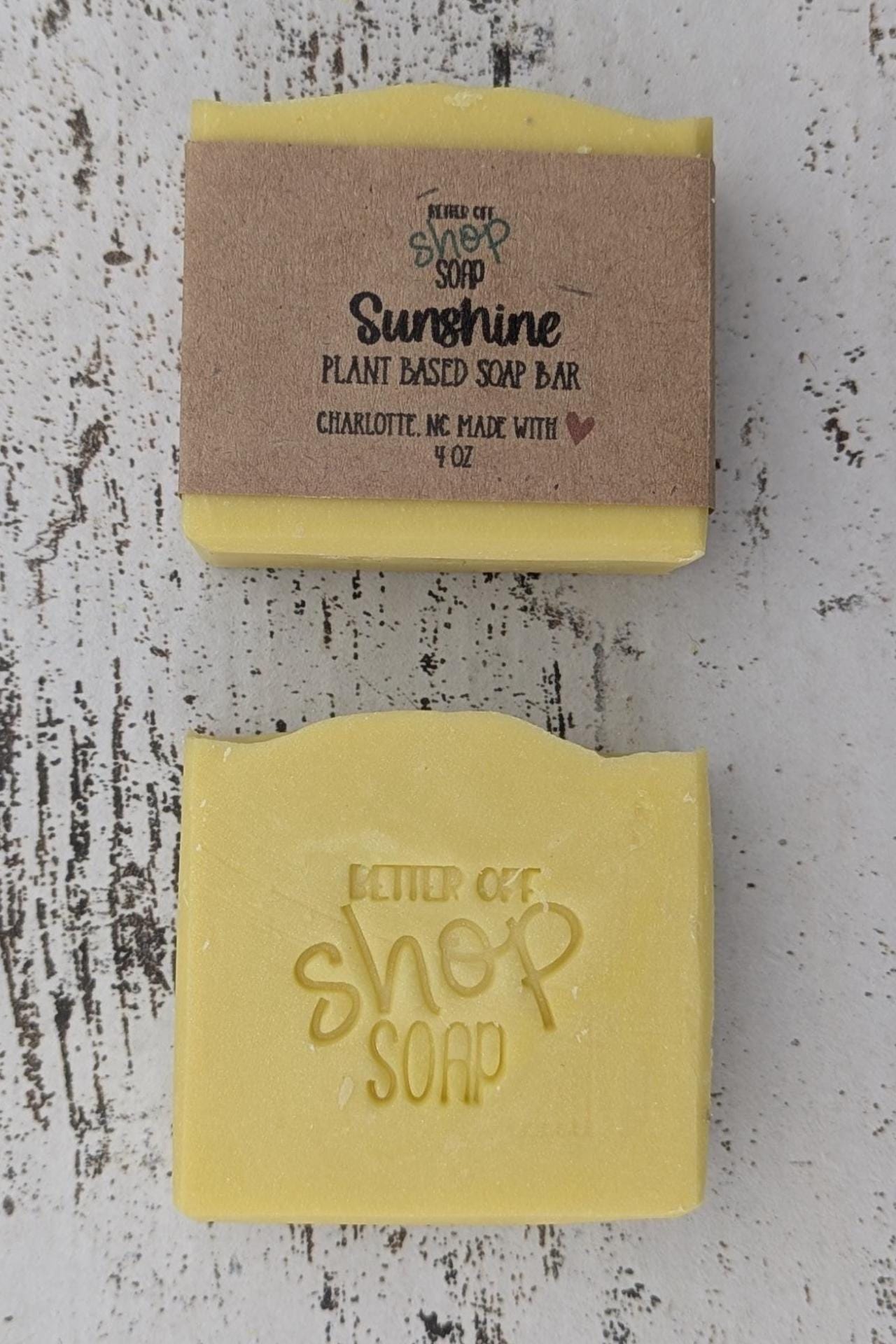 A vibrant yellow handmade cold process soap bar with beveled edges, wrapped in a recyclable paper band. The soap has a fresh, fruity citrus scent with notes of mandarin oranges, bergamot, tangerine, peaches, strawberries, raspberries, and white musk. Made with plant-based ingredients like castor oil, coconut oil, olive oil, and shea butter for a moisturizing lather. Ideal for eco-conscious skincare and daily self-care.