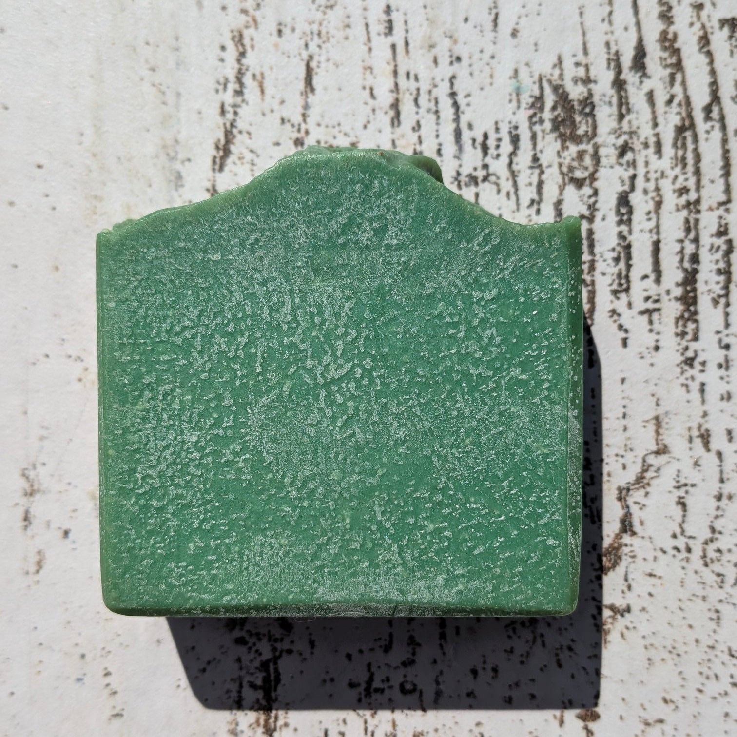 Green square tile on a textured white surface