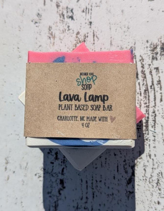 Handmade vegan soap with vibrant swirls of pink, blue, and white, resting on a wooden surface