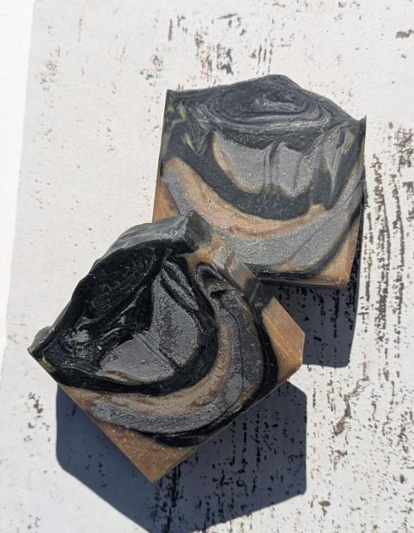 A rustic setting with natural lighting, drawing attention to the soap’s bold swirls and deep mahogany coconut scent inspiration.