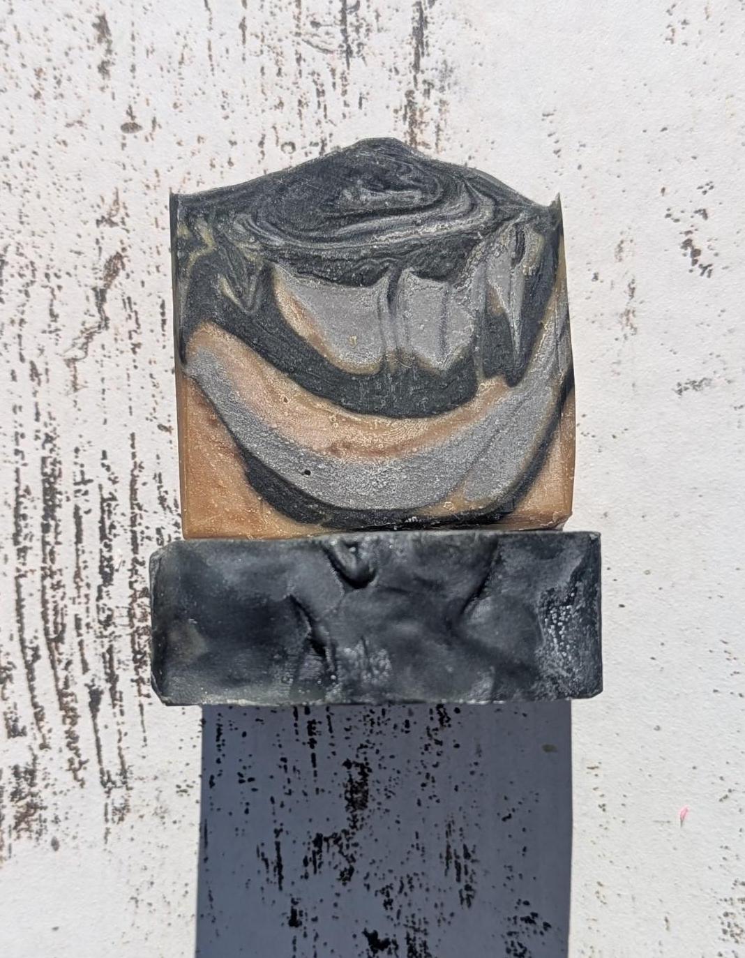 A rustic setting with natural lighting, drawing attention to the soap’s bold swirls and deep mahogany coconut scent inspiration.