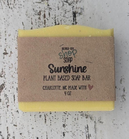 A vibrant yellow handmade cold process soap bar with beveled edges, wrapped in a recyclable paper band. The soap has a fresh, fruity citrus scent with notes of mandarin oranges, bergamot, tangerine, peaches, strawberries, raspberries, and white musk. Made with plant-based ingredients like castor oil, coconut oil, olive oil, and shea butter for a moisturizing lather. Ideal for eco-conscious skincare and daily self-care.