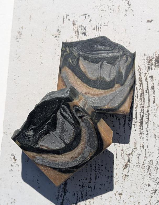 A rustic setting with natural lighting, drawing attention to the soap’s bold swirls and deep mahogany coconut scent inspiration.