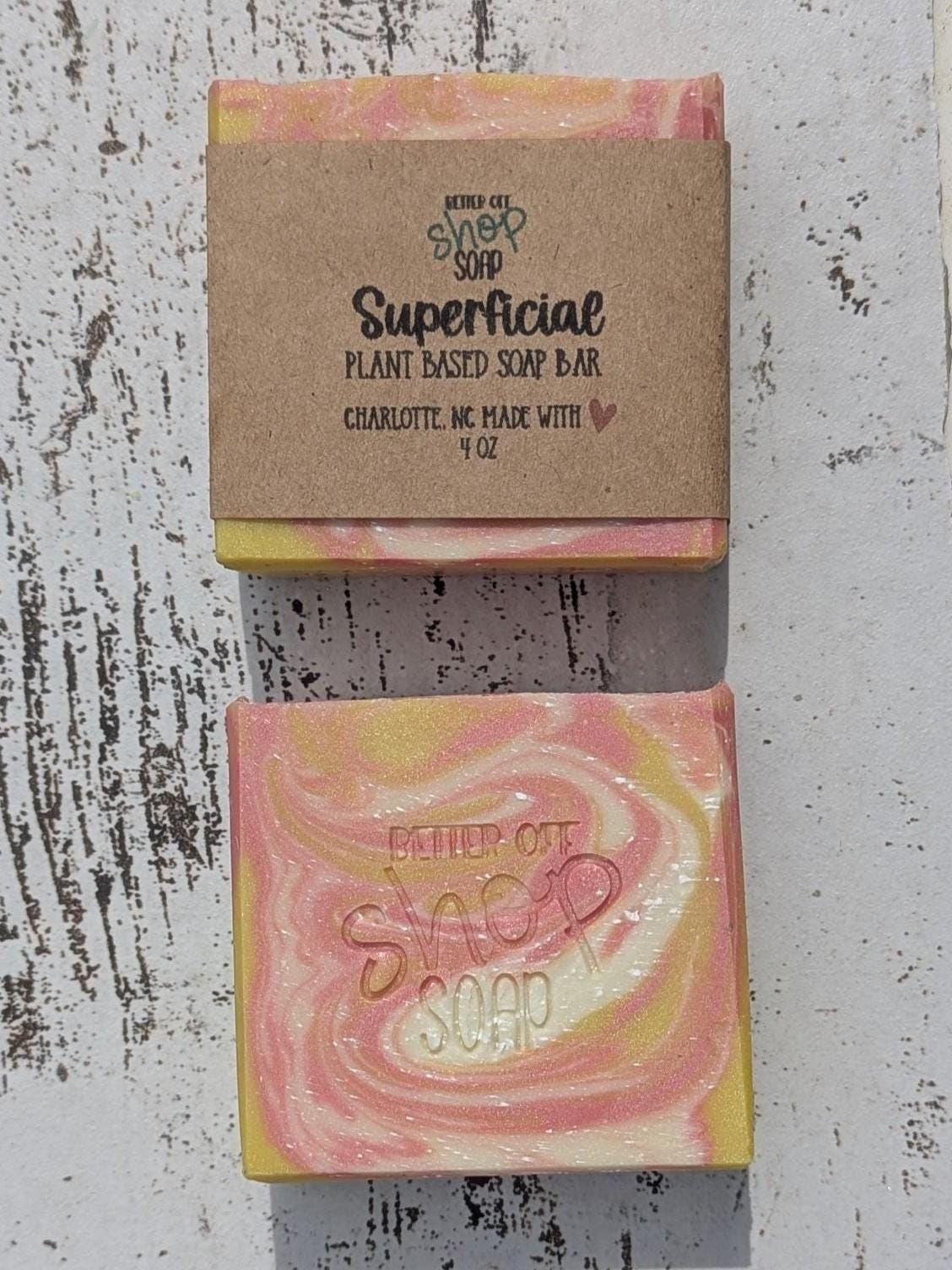 Close-up of two cold process soap bars showing intricate pink, yellow, and white swirls made with skin-safe micas. Smooth finish with visible texture from the swirl pattern.