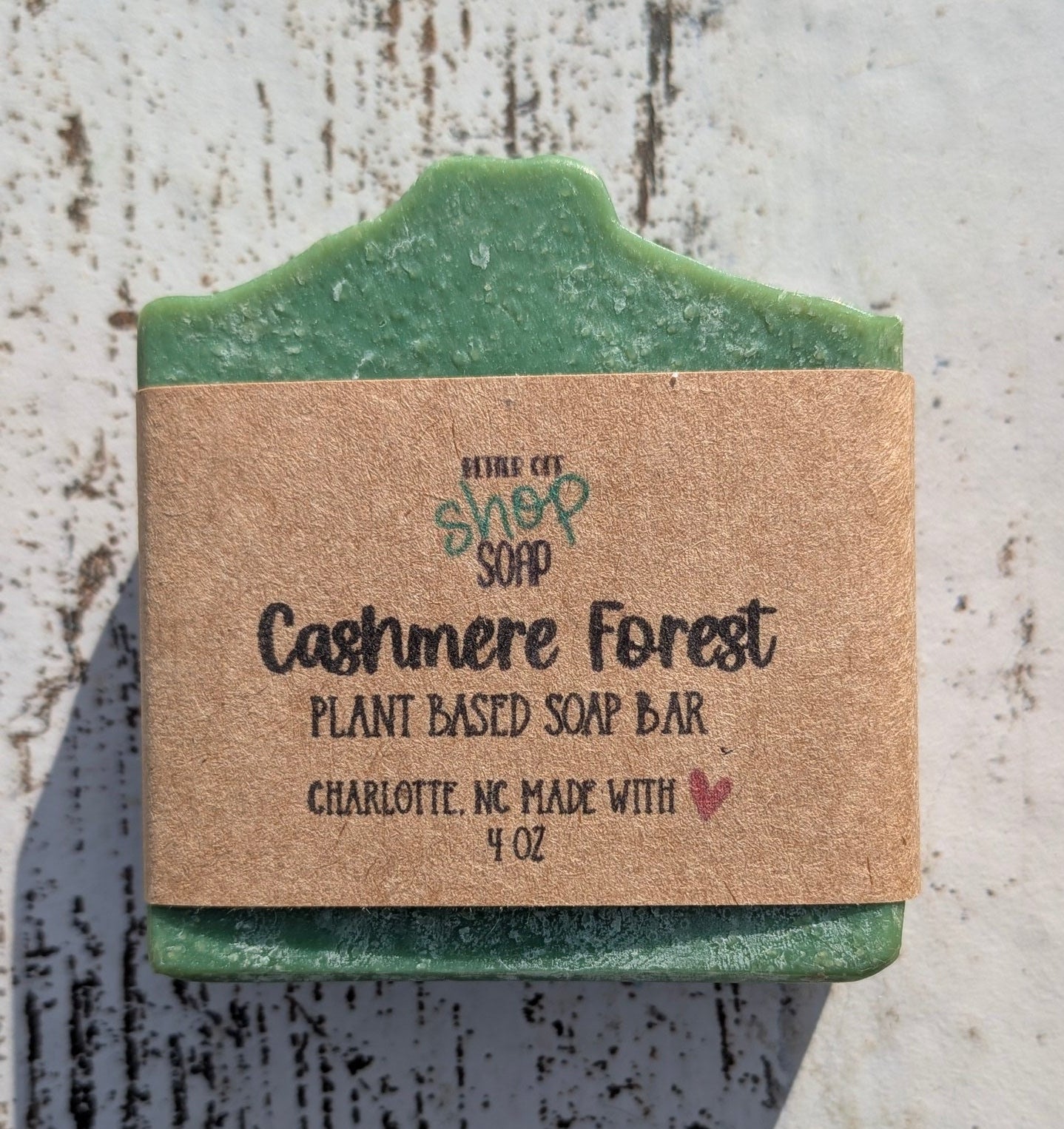 Green bar of soap with a cardboard label on a textured surface