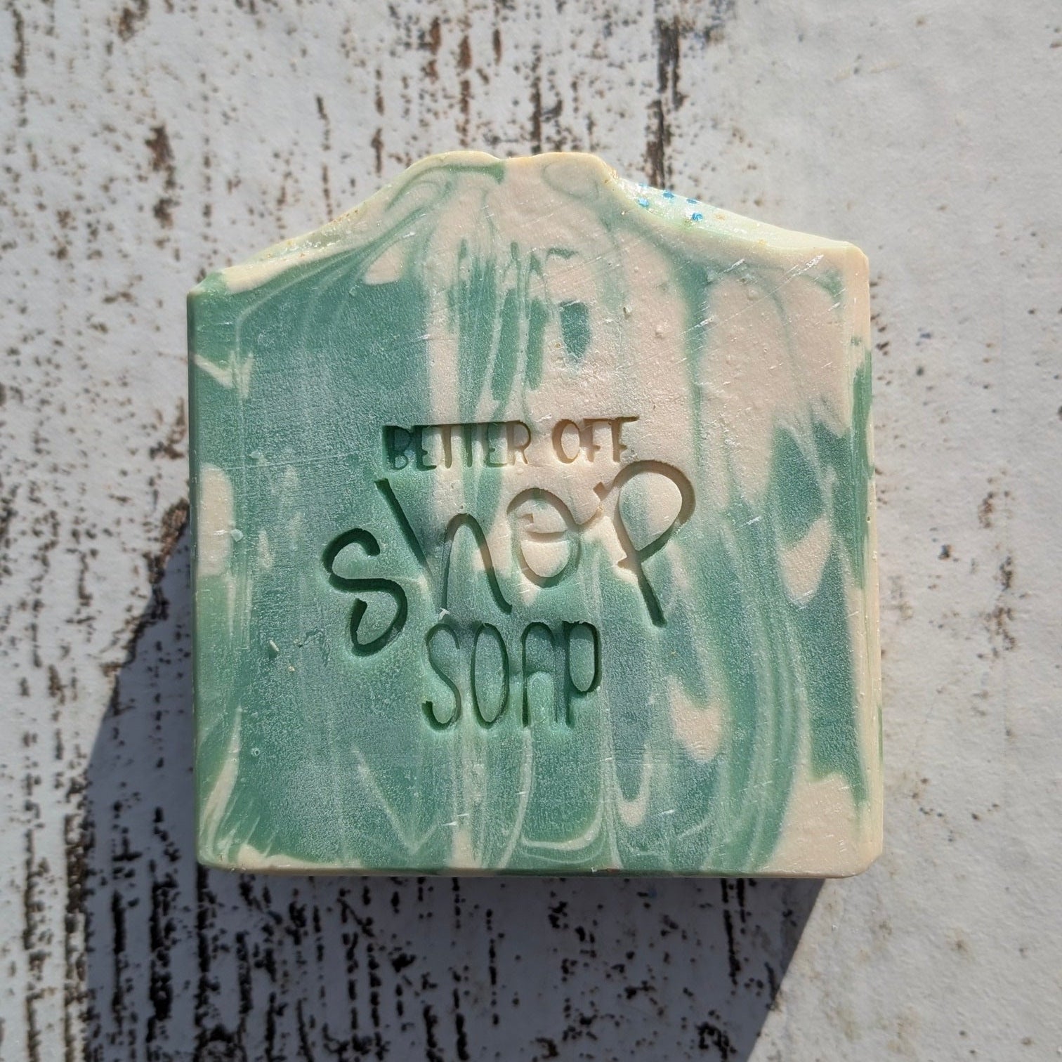 Bar of soap with 'Better Off Soap Shop' branding on a textured surface