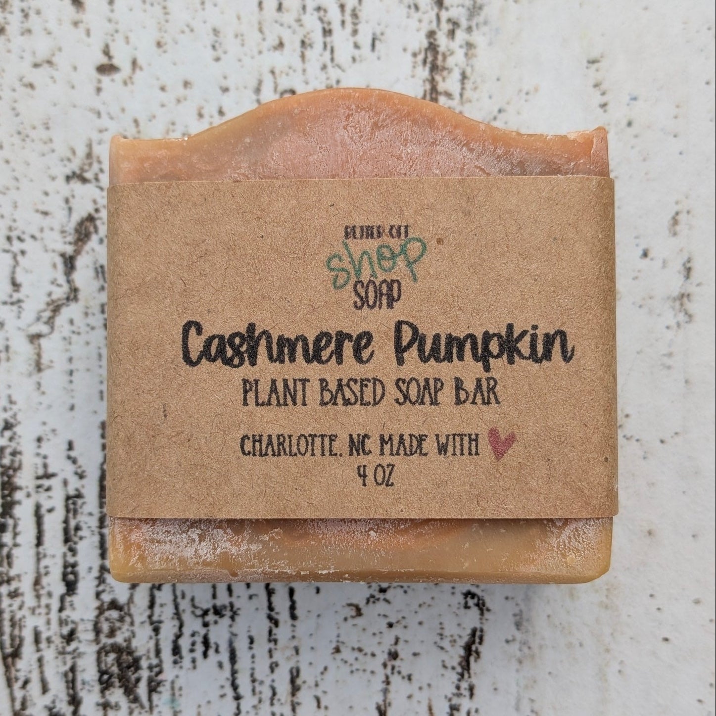 Bar of soap with a cardboard wrapper on a textured white surface