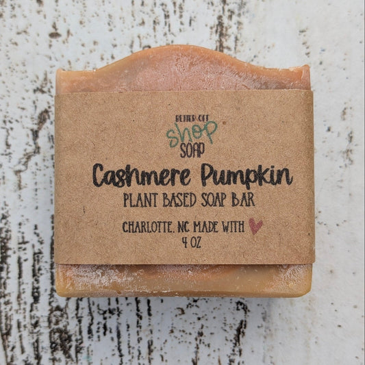 Bar of soap with a cardboard wrapper on a textured white surface