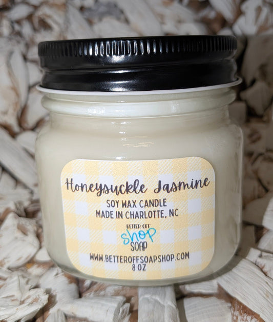 Jar of Honeysuckle Jasmine candle with a black lid on a textured surface