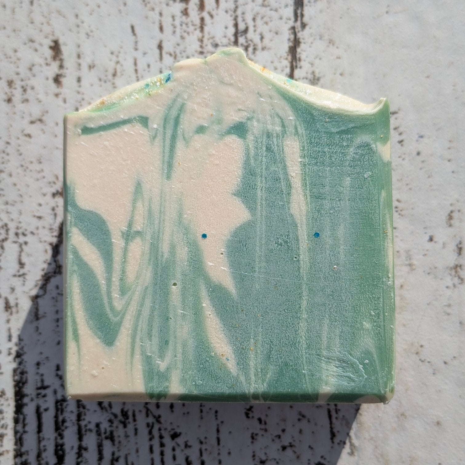 Marbled green and white soap bar on a textured surface